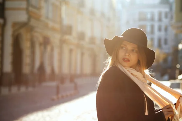 スタイリッシュな金髪女性を着て帽子 マフラー コート 太陽光線の古い通りを歩いてします テキストのためのスペース — ストック写真