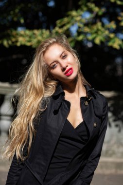 Siyah palto ve şehir, güneş ışınlarının poz elbise giyen parlak makyaj ile muhteşem sarışın kadın