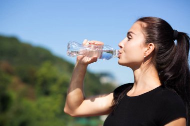 Fitness kadın içme suyu güneşli sabah parkta çalıştırma sırasında çarpıcı. Boş alan