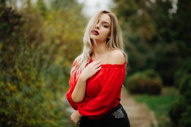 Kırmızı bluz, mazı ağaçlarının çıplak omuz ile poz güzel sarışın model