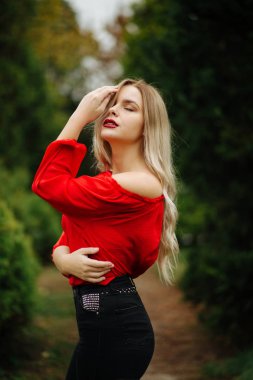 Harika sarışın model Kırmızı bluz, mazı ağaçlarının çıplak omuz ile poz içinde
