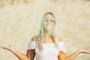 Çölde yeşil Holi boya patlayan ile poz gözlüklü ifade sarışın kadın