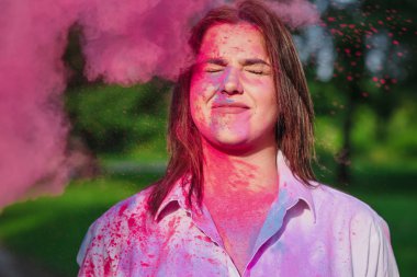 Serin genç kafkas kadın parkta Holi Festivali pembe kuru boya ile oynarken