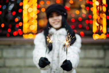 Korku veren genç kadın havai fişekleri bulanık şehir ışıkları ile yeni yıl kutlama