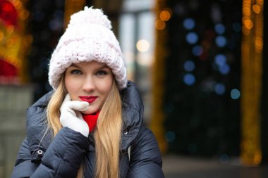 Sokağın bokeh ile bir çelenk arka plan üzerinde poz örme şapkası kırmızı ruj çok güzel sarışın kadın