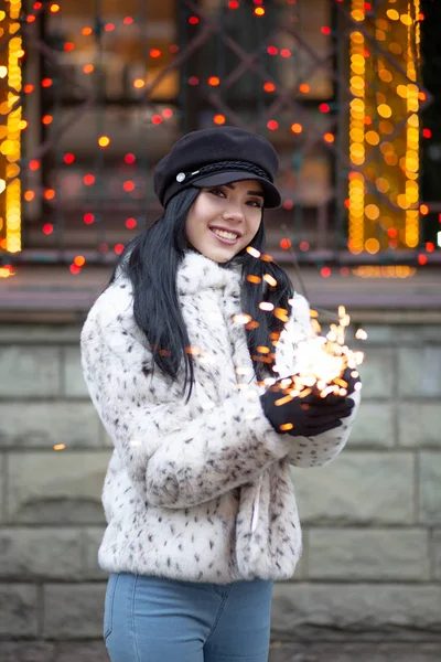 Harika gülümseyen esmer kadın havai fişekleri ile eğleniyor çelenk arka plan bulanık trendy şapkası 