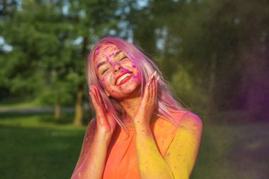 Güzel sarışın kadın parkta renkli kuru boya ile eğleniyor. Festival Holi için kavramı