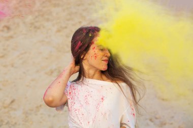 Holi renkler Çölü festivalde kutluyor mutluluk genç kadın sarı kuru toz bulutu içinde eğleniyor