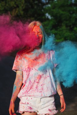 Harika sarışın kadın Holi festival kutluyor patlayan mavi ve pembe kuru toz ile eğleniyor