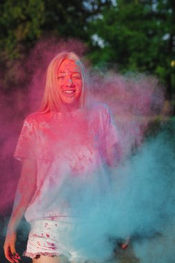 Holi festival kutluyor patlayan mavi ve pembe kuru toz ile eğleniyor neşeli sarışın kadın