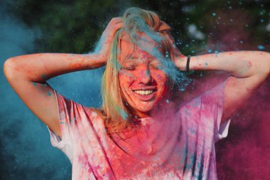 Holi festival kutluyor patlayan mavi ve pembe kuru toz ile eğleniyor duygusal sarışın kız