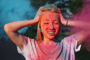 Holi festival kutluyor patlayan mavi ve pembe kuru toz ile eğlenmek çok güzel sarışın kız