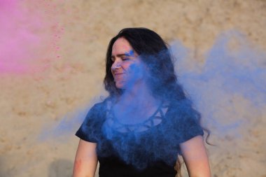 Onun mavi ve pembe Holi toz, çölde etrafında patlayan ile poz güzel genç kadın