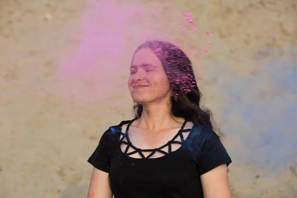 満足している若い女性が砂漠で彼女の青とピンクのホーリー パウダーの周り爆発ポーズ — ストック写真