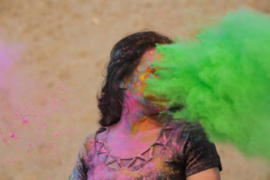 Uzun dalgalı saçlı yeşil kuru Holi toz ile eğleniyor çöl çarpıcı esmer kız