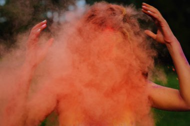 Etrafındaki turuncu kuru Holi boya ile oynayan beyaz t gömlek giyen genç redhaired kadın
