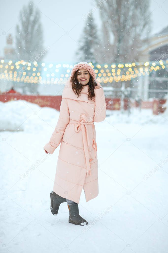 Winter portrait of pretty brunette young woman wearing warm trendy outfit, walking at the Christmas fair in Kiev