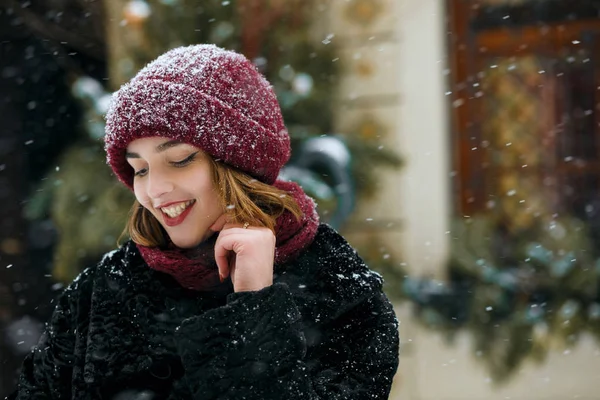 可爱的微笑黑发女人戴着红色的帽子在街上摆姿势在下雪 空白空间 — 图库照片