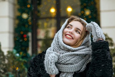 Excited brunette woman wearing grey scarf enjoying winter holidays. Empty space