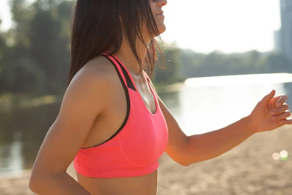 Young sporty woman doing cardio workout at the beach. Closeup shot