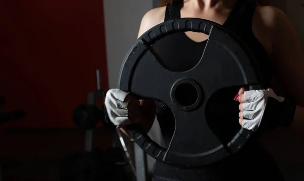 Fitness woman taking barbell plates during training. Space for text