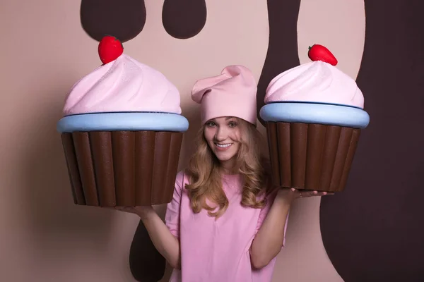 Aufgeregtes Blondes Mädchen Mit Pinkfarbener Mütze Genießt Große Cupcakes Studio — Stockfoto