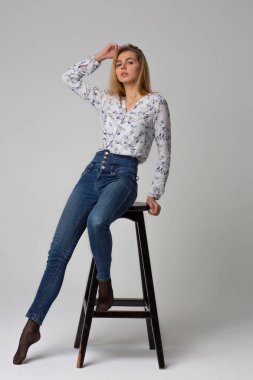 Baştan çıkarıcı genç kadın için atış tam uzunlukta testi mavi kot pantolon ve gömlek giyer