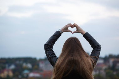 Şehir arka plan üzerinde eller genç uzun saçlı kadın gösteren kalp simgesini iki ile. Boş alan
