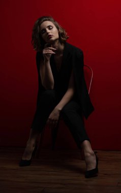 Karşıtlık kırmızı arka plan ışık ile poz dalgalı kısa saçlı esmer kadın şaşırtıcı