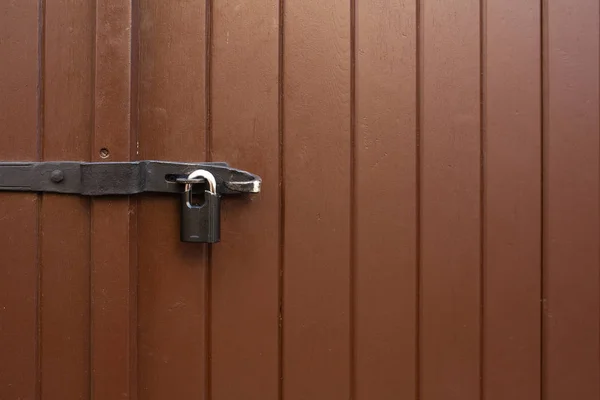 Painted wooden door with a hanging iron lock outdoor. Empty space
