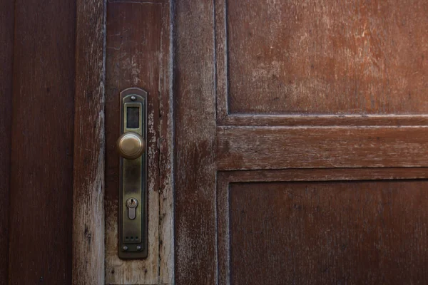 Bronze metal door handle of a brown scratched door. Empty space