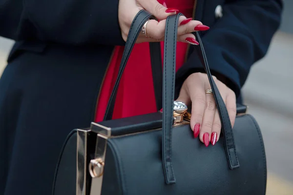 Femme portant élégant manteau bleu ouvrant sac à main en cuir noir. Emp. — Photo