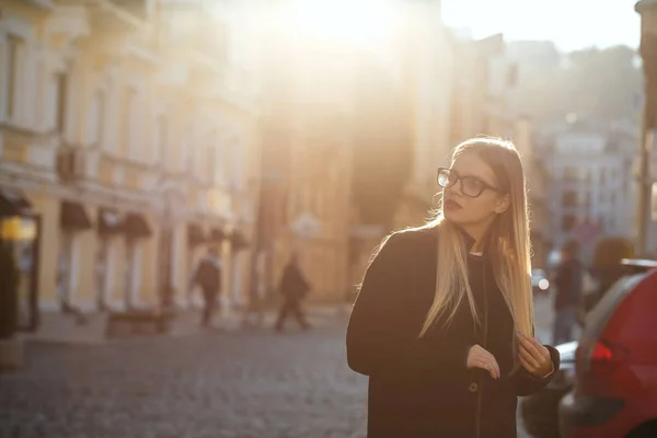 Pretty blonde girl with long hair wearing coat, posing in sun gl — Stock Photo, Image