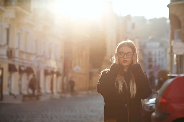Lovely blonde girl with long hair wearing coat, posing in sun gl — Stock Photo, Image