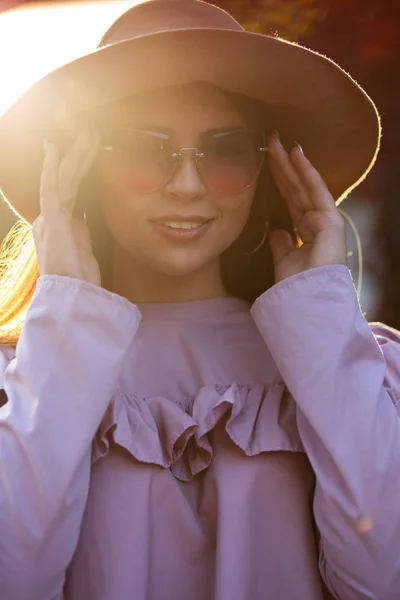 Cheerful brunette girl wearing hat and sunglasses, posing at sun — Stock Photo, Image