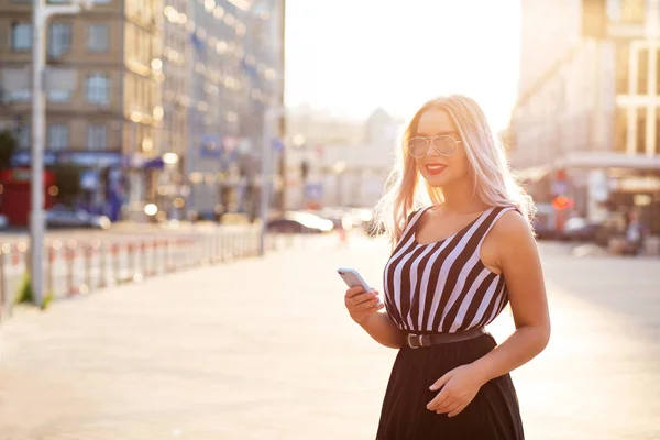 सुंदर मुस्कुराते सुनहरे बालों वाली मॉडल मोबाइल फोन टाइपिंग messag पकड़े हुए — स्टॉक फ़ोटो, इमेज