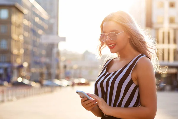 Pretty smiling girl holding mobile phone typing message at the c — Stock Photo, Image