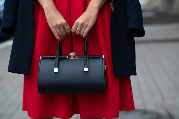 Mujer con elegante vestido rojo y abrigo que sostiene el cuero negro p —  Fotos de Stock