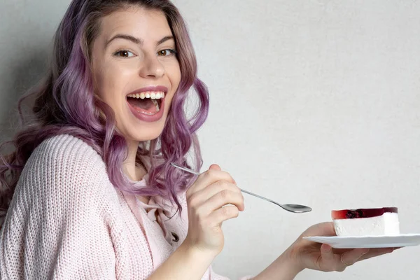 Enthousiast jong meisje met paars haar eten smakelijke kaas taart ove — Stockfoto