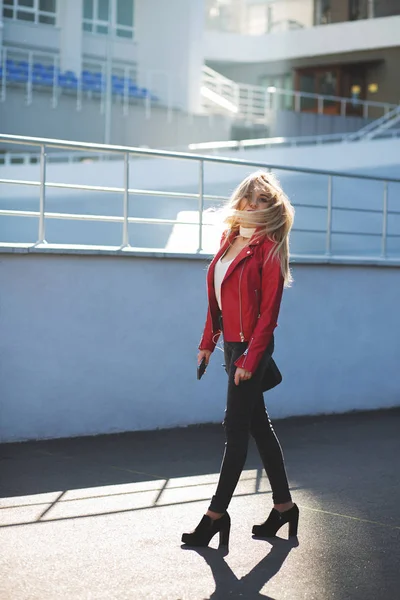 Impresionante chica rubia con chaqueta roja caminando por la calle w —  Fotos de Stock