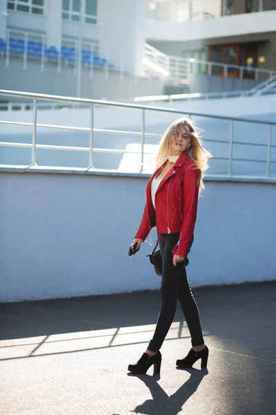 Fille blonde élégante portant une veste rouge marchant dans la rue w — Photo