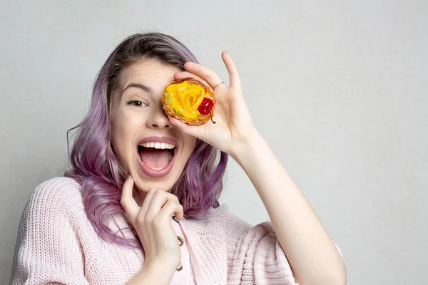 Ενθουσιασμένος νεαρή κοπέλα με μοβ μαλλιά που καλύπτει τα μάτια της από γλυκό de — Φωτογραφία Αρχείου