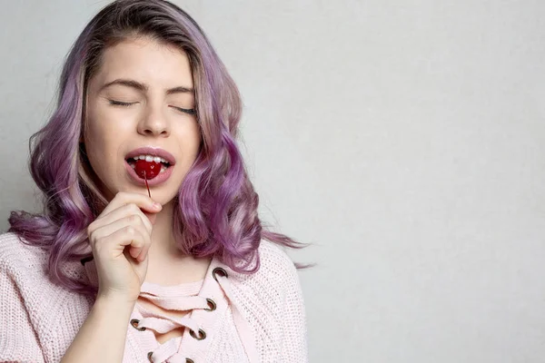 Mooi blij meisje met golvende paars haar genieten van kers. Empt — Stockfoto