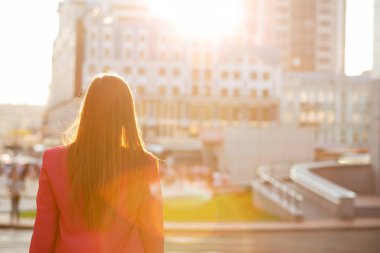 Şehir binaları ile yumuşak güneş arayan genç esmer kız 