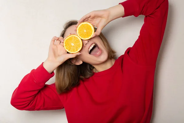 Grappige brunette meisje poseren met een halve sinaasappel, die betrekking hebben op ogen wit — Stockfoto