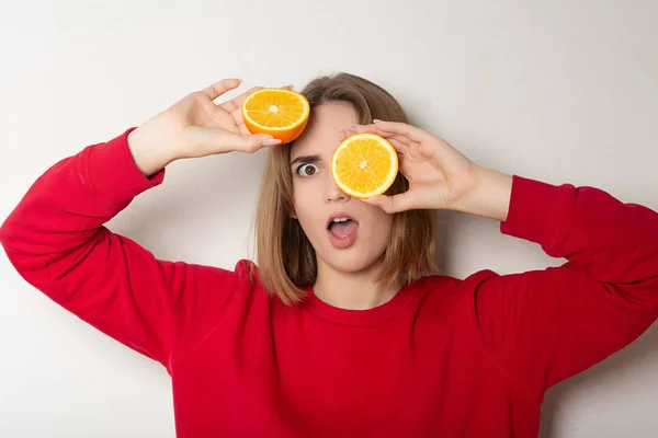 Verrast brunette meisje poseren met een halve sinaasappel, die betrekking hebben op ogen — Stockfoto