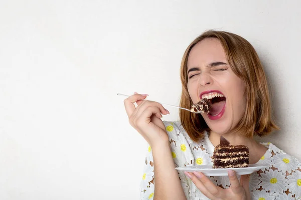 Funny young girl eating tasty chocolate cake over white backgrou — Stock Photo, Image