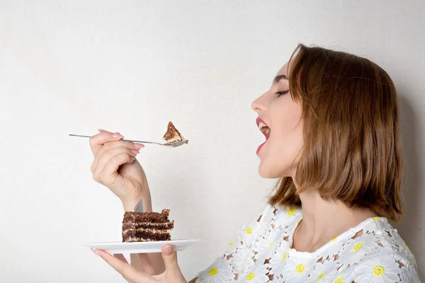 Pleased brunette lady with natural makeup eating sweet chocolate