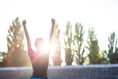 Günbatımı karşı sportif koşucu kız el zafer sembolü. Girintili
