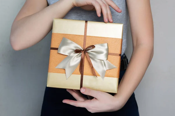 Caucasian young girl wearing t shirt holding gift box with a bow — Stock Photo, Image